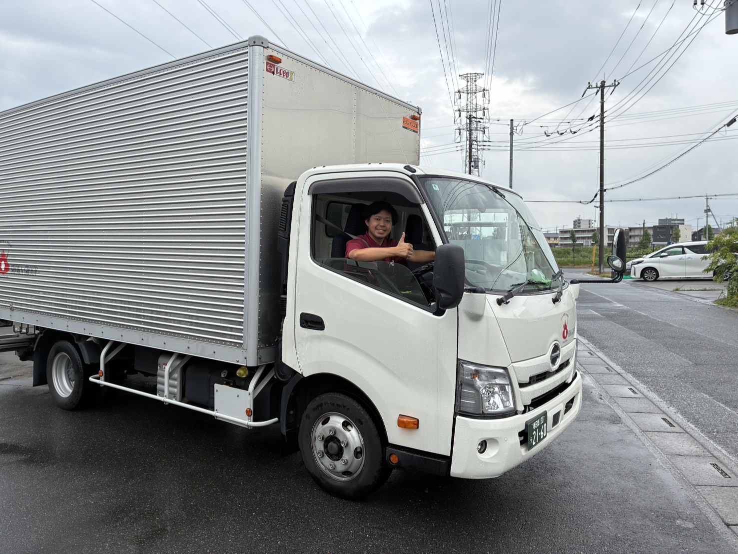トラックの運転席から笑顔で手を上げるSHOKA GROUPの従業員